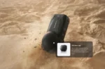 دوربین Insta360 X6 مشکی با درپوش لنز در تصویر رسمی روی شن